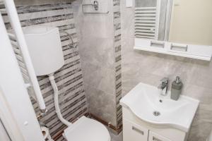 La salle de bains est pourvue de toilettes blanches et d'un lavabo. dans l'établissement ĐILL Apartment, à Subotica