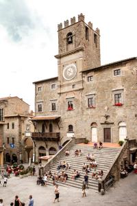 un grupo de personas sentadas en las escaleras en un edificio con una torre del reloj en Casa Quintani, en Cortona