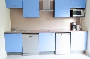 eine Küche mit weißen Geräten und blauen Schränken in der Unterkunft Appartement 4 personne sur Parc Vacances Richelieu in Chaveignes
