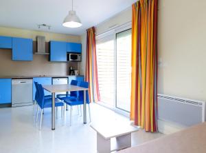 eine Küche mit blauen Schränken sowie einem Tisch und Stühlen in der Unterkunft Appartement 4 personne sur Parc Vacances Richelieu in Chaveignes