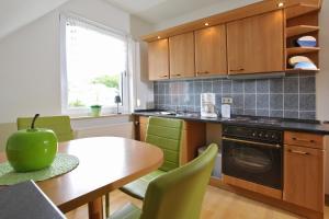 a kitchen with wooden cabinets and a table with green chairs at Haus Am See in Baabe