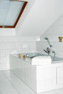 a bath tub in a white tiled bathroom at Ferienwohnungen Franziska Hackl in Bad Birnbach