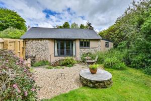 a stone house with a table in the yard at The Bothy - a cosy little rustic barn in Parracombe