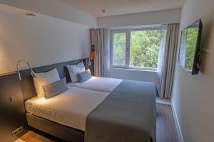 a bedroom with a large bed with a window at Hotel Landgoed Zonheuvel in Doorn