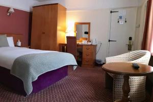 a bedroom with a bed and a table and a desk at The Tudor Hotel in Harrow
