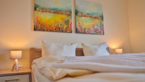 a bedroom with a bed with two paintings on the wall at Wohnung "Stralsund" in Gützkow