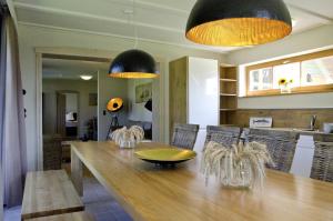a dining room with a wooden table and black pendant lights at Ferienwohnungen Boddenfischer in Born