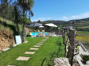 a garden with a swimming pool and palm trees at Estúdio de Amor in Castelo de Paiva
