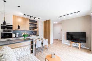 a living room with a couch and a kitchen with a tv at Apartament Kochanowskiego z ogródkiem i garażem - Dream Apart in Ustroń