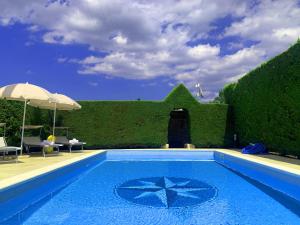 a blue swimming pool with a hedge and an umbrella at Villa parco la Ruta, Piscina e relax in Noci
