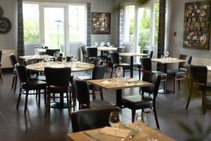 a restaurant with tables and chairs with wine glasses on them at Hôtel Relais d'Étretat in Bolbec