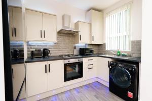 a kitchen with white cabinets and a washer and dryer at Richmond House in Leeds