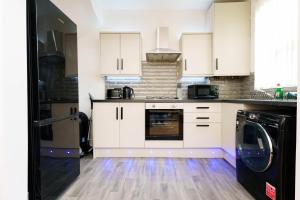 a kitchen with white cabinets and a black dishwasher at Richmond House in Leeds
