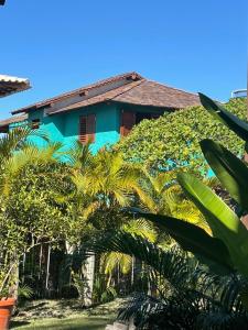 a blue house with palm trees in front of it at Mirante Caraiva in Caraíva