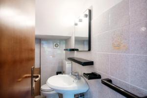 een badkamer met een wastafel, een toilet en een spiegel bij The sound of silence in Pognana Lario
