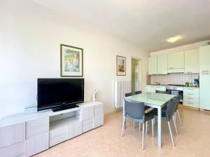 uma sala de estar com televisão e uma mesa com cadeiras em Appartamenti Valle Dolce Carraro Immobiliare - Family Apartments em Cavallino-Treporti