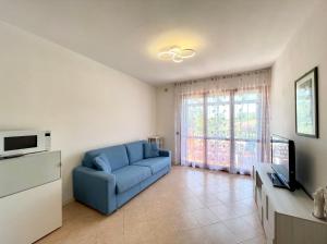 uma sala de estar com um sofá azul e uma televisão em Appartamenti Valle Dolce Carraro Immobiliare - Family Apartments em Cavallino-Treporti