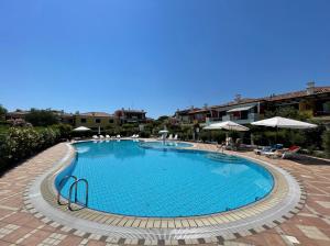 uma grande piscina com cadeiras e guarda-sóis em Appartamenti Valle Dolce Carraro Immobiliare - Family Apartments em Cavallino-Treporti