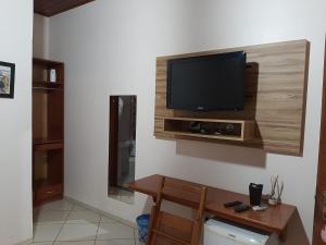 a living room with a television on a wall at Hotel da Gaúcha in Tucuma