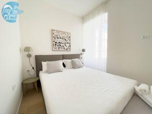 a white bedroom with a large bed with white sheets at Slataper 12 Tirabora Short Rent in Trieste
