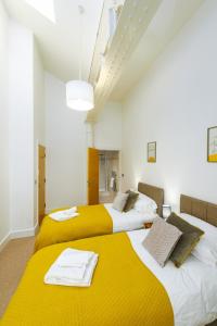 two beds with yellow sheets in a room at K Suites - Barton Court in Warrington