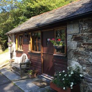 a cabin with a bench and flowers in the window at Romantic, secluded cottage in Cardinham Woods, Cornwall in Cardinham