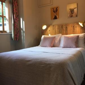una camera da letto con un letto grande con lenzuola e cuscini bianchi di Romantic, secluded cottage in Cardinham Woods, Cornwall a Cardinham