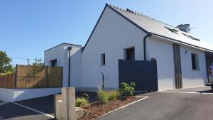 a white house with a black door in a parking lot at AMARRÉ Chambres d'Hôtes in Sarzeau