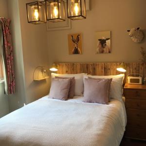 una camera da letto con un letto con lenzuola e cuscini bianchi di Romantic, secluded cottage in Cardinham Woods, Cornwall a Cardinham Altre 12 foto