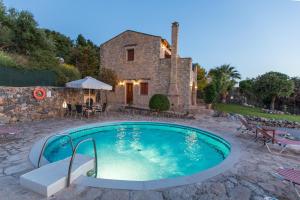 Agia Triada的住宿－Cretan Exclusive Villas，石头房子前面的游泳池