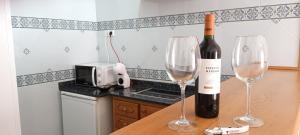 a bottle of wine and two wine glasses on a counter at Hotel Nou Can Guillem in Cala Figuera