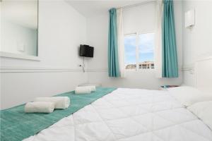 a white bedroom with a large bed with two pillows at Hostal Brisa Marina in Port d'Alcudia
