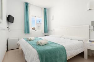 a white bedroom with two beds with towels on it at Hostal Brisa Marina in Port d'Alcudia