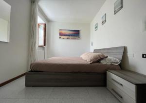 a bedroom with a bed and a dresser in it at Spiaggia - nuovo appartamento elegante - Lago di Garda in Padenghe sul Garda