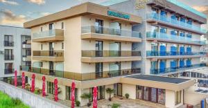 un edificio de apartamentos con banderas rojas delante de él en Roca Del Mar, en Mamaia Nord – Năvodari