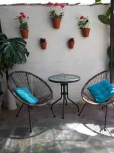 La Posada Amena في Carcabuey: فناء فيه كرسيين وطاولة وبعض النباتات