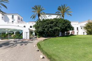 a large white building with palm trees and a yard at Sighientu Resort in Capitana