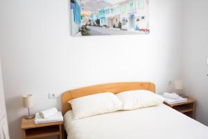 1 dormitorio con 1 cama con sábanas blancas y espejo en JTP Apartmani Ivanjica, en Ivanjica