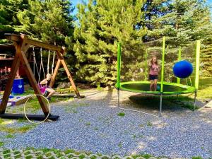 een meisje staat op een schommel in een speeltuin bij Mobilný domček in Terchová