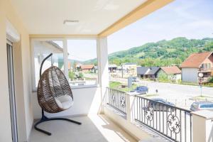 a chair on a balcony with a view of a street at JTP Apartmani Ivanjica in Ivanjica