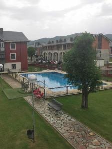 a swimming pool with a tree and a building at Apartamento de 3 dormitorios con piscina - Riaza Vacacional in Riaza