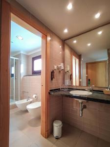 a bathroom with a sink and a toilet and a mirror at Ohtels Campo De Gibraltar in La Línea de la Concepción