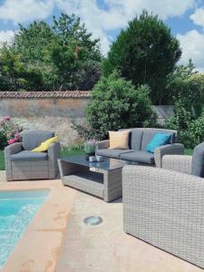 a patio with two couches and a table next to a pool at Très joli appartement équipé au calme in Rozay-en-Brie