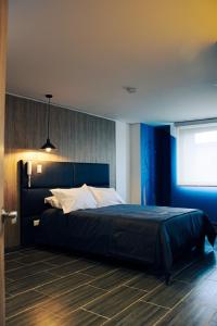 sypialnia z dużym łóżkiem z niebieskimi ścianami w obiekcie Estainn Hotel Coworking w mieście Bogota
