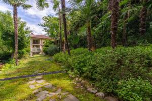 una casa in mezzo a un cortile con palme di La dependance immersa nel parco della Villa Isabella a Stresa