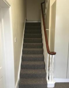 una escalera con alfombra gris y barandillas de madera en Camden Apartments, en Londres