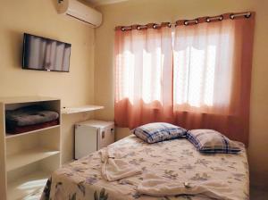 um pequeno quarto com uma cama e uma janela em Hotel Janaína em Porto Belo