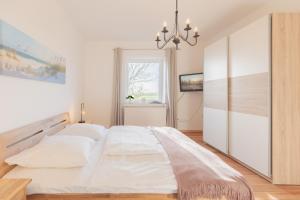 een slaapkamer met een groot wit bed en een kroonluchter bij Grenzhaus am See in Rosenkranz