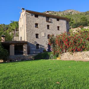 ein großes Steingebäude mit roten Blumen im Hof in der Unterkunft El Molinet del Governador in Guadalest