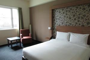 una camera d'albergo con un letto grande e una sedia di Strand Hotel a Singapore